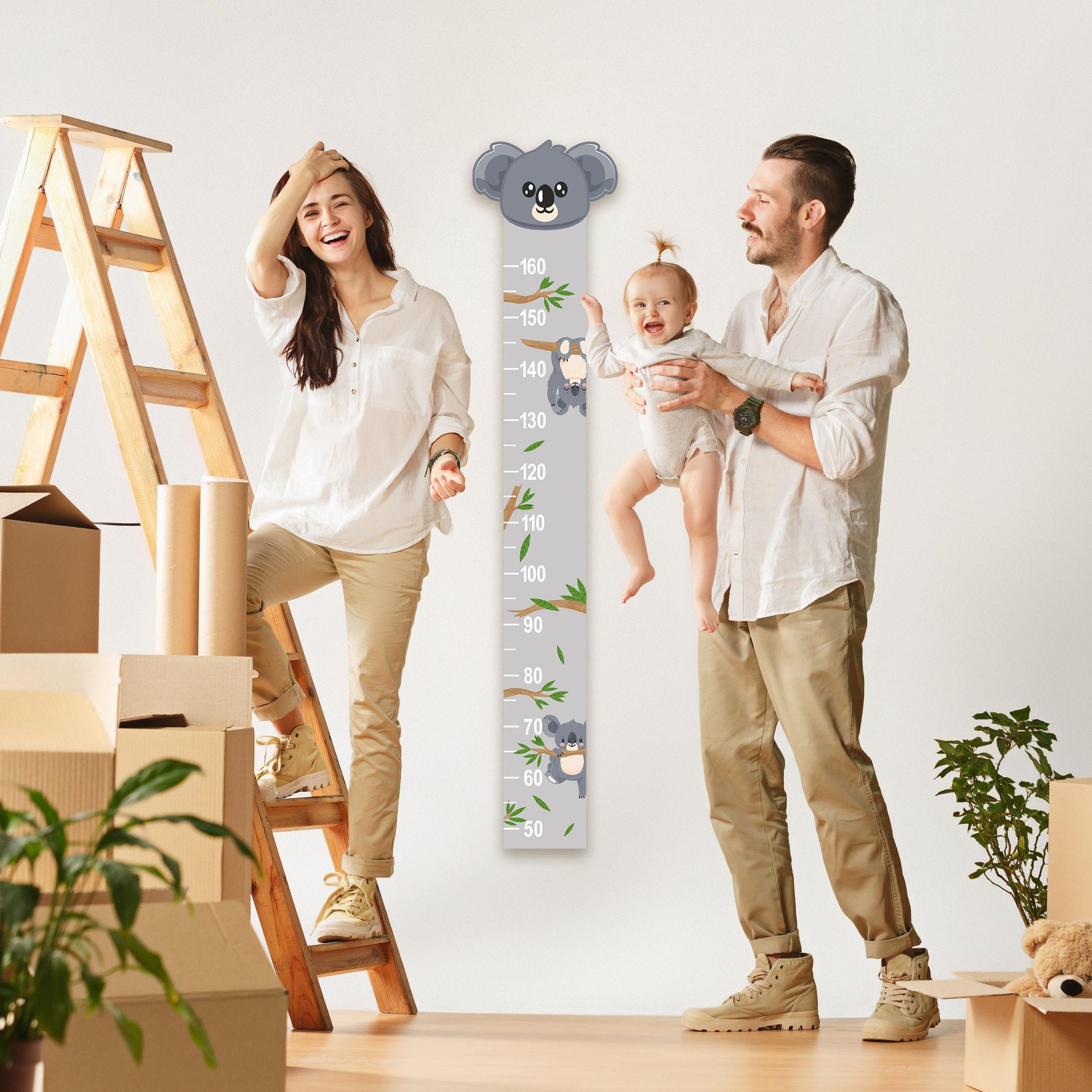 a man and woman holding a baby next to a Koala growth chart